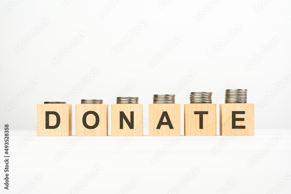 donnate text written on wooden block with stacked coins on white background, growing trend donnate text written on wooden block with stacked coins on white background, growing trend