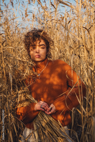 Portrait of beautiful young woman outdoor posing in the reeds and holding bouquet