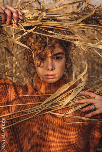 Portrait of a beautiful young woman posing outdoor and holds bouquet of reeds