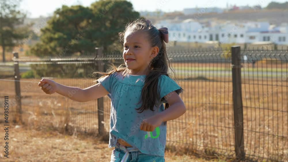 Niña feliz jugando volando el papalote el cometa con el aire disfrutando en el parque al aire libre en el exterior aprendiendo conociendo el mundo