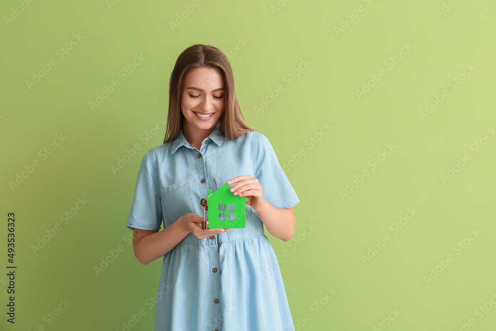 Smiling young woman with key from house on green background Smiling young woman with key from house on green background
