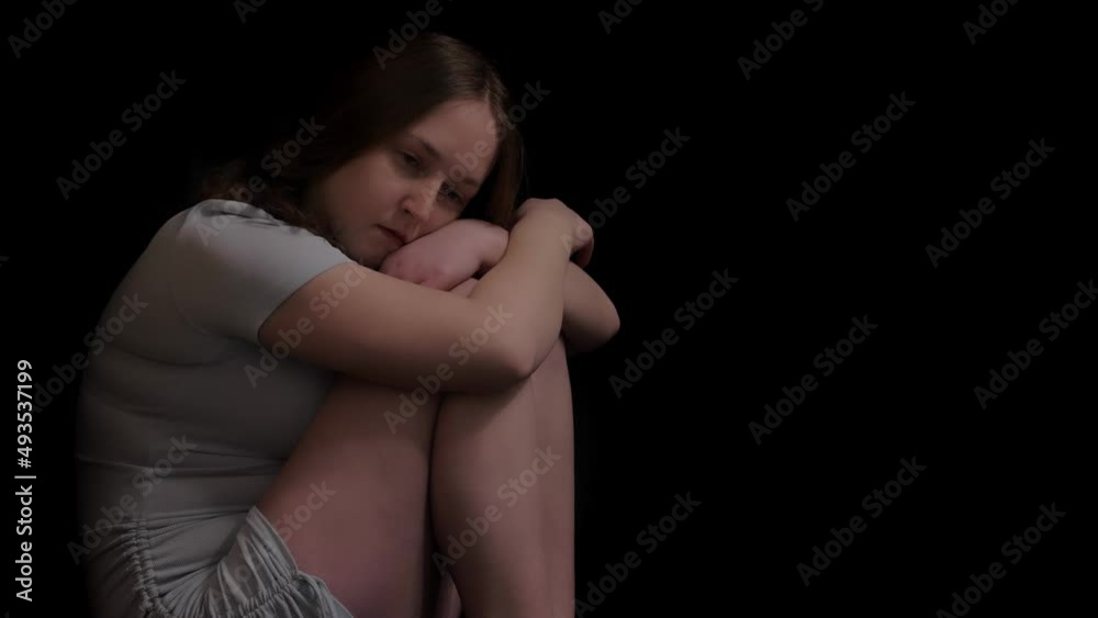 Young girl in white shorts sitting on the dark floor in the corner of the house sadly ponders about work problems. Young girl in white shorts sitting on the dark floor in the corner of the house sadly ponders about work problems.