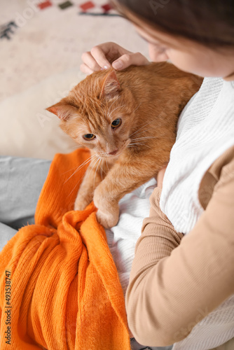 Woman with cute ginger cat at home on autumn day