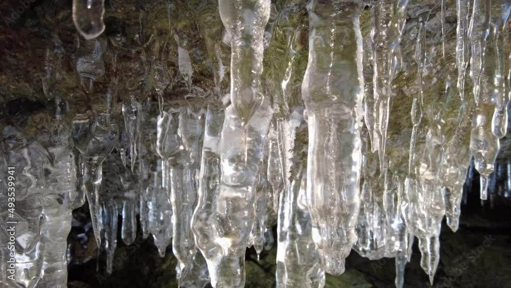 Ice cave on Baikal lake in winter. Clear transparent ice and icicles in grotto. Olkhon island, Baikal, Siberia, Russia, 4k
