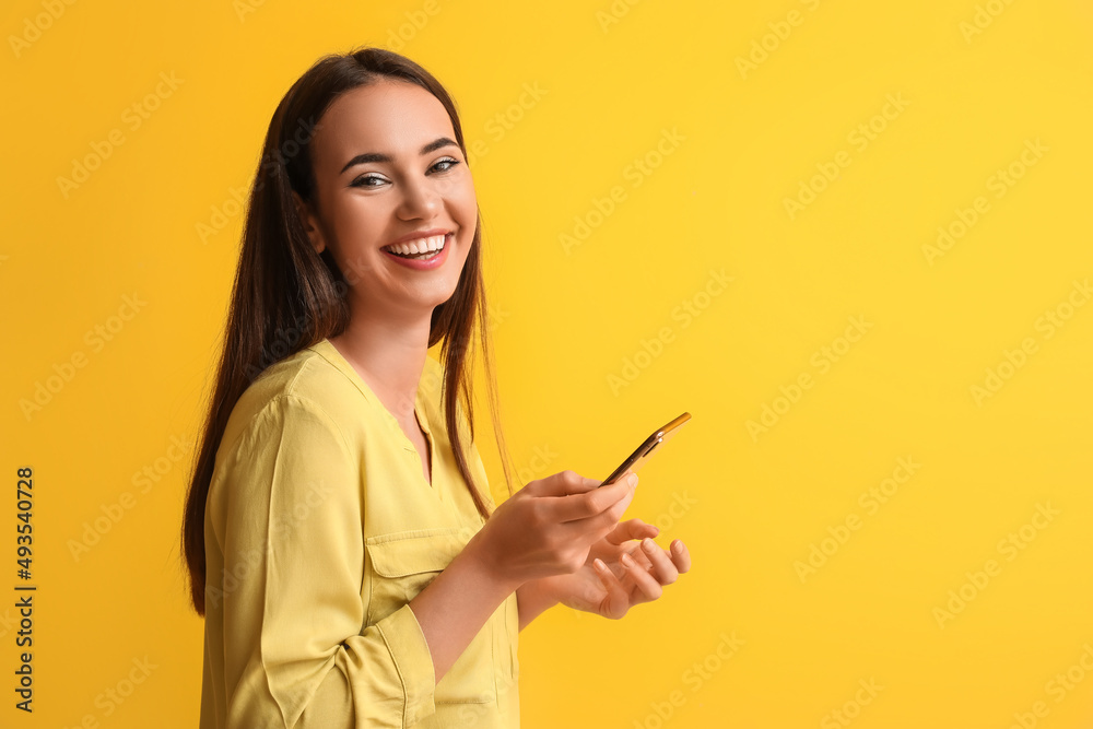 Beautiful young woman with mobile phone on yellow background Beautiful young woman with mobile phone on yellow background