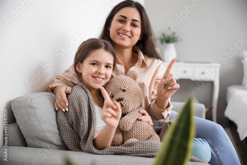 Fotografie Mother applying remedy on skin of her little daughter ill with chickenpox at hom