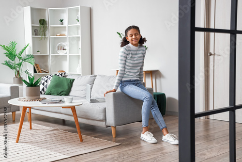African-American teenage girl sitting on sofa at home © Pixel-Shot