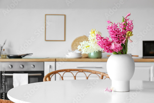 Vase with hyacinth flowers on dining table in kitchen