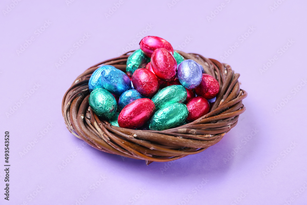 Nest with different chocolate Easter eggs on lilac background Nest with different chocolate Easter eggs on lilac background