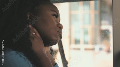 Side view of an African American mysterious disappointed resentful sad young woman looking out windows