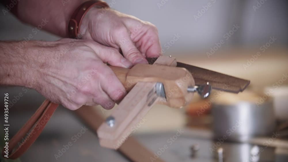 The tailor cuts a piece of leather using an instrument The tailor cuts a piece of leather using an instrument