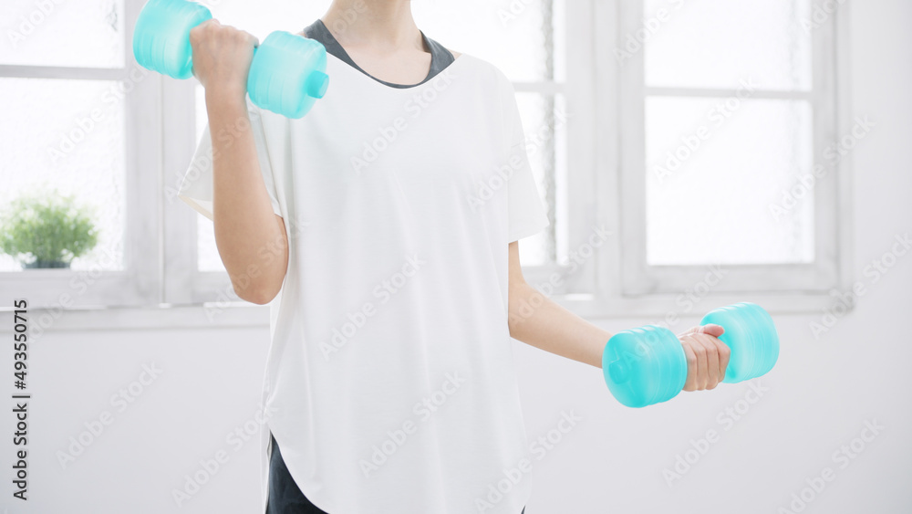 ダンベルを使って筋トレをする女性 ダンベルを使って筋トレをする女性