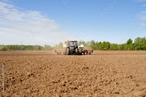 Sowing the land. Shot of a tractor seeding a large plowed field on a farm.