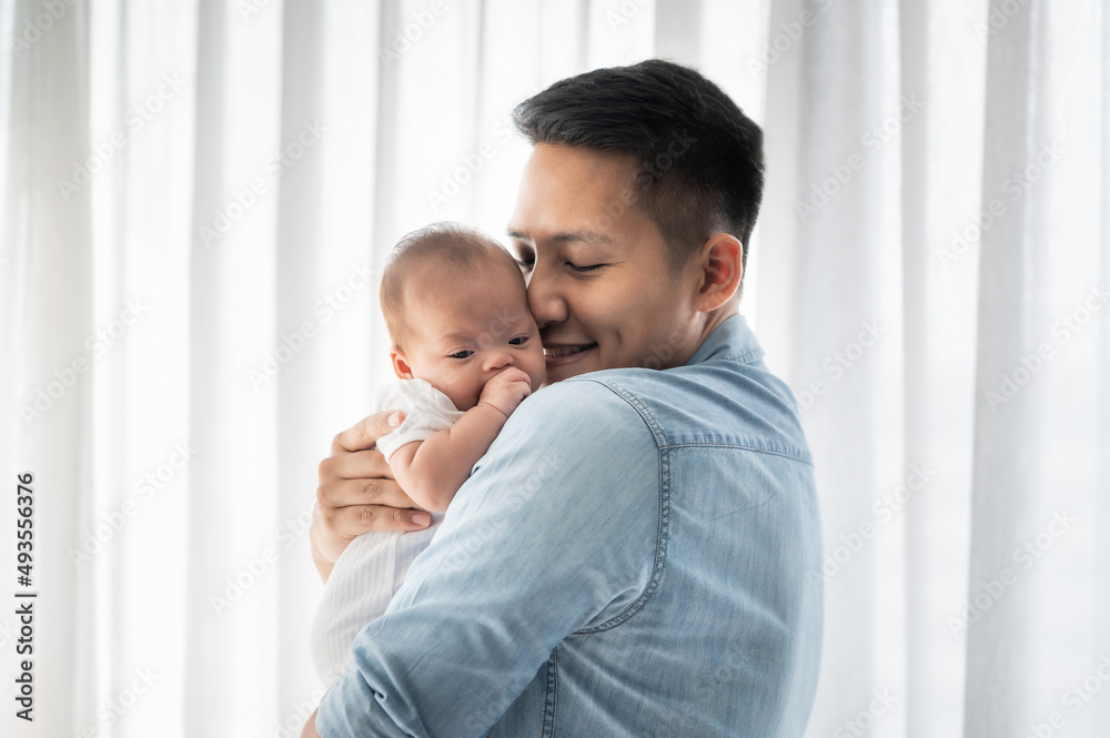 Asian father holding baby daughter and kissing with love at home Asian father holding baby daughter and kissing with love at home