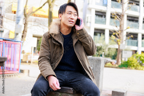 公園で電話をするハンサムな日本人男性