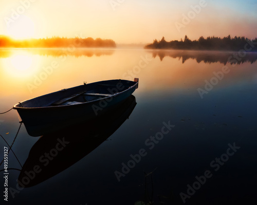 Fotografia The first minutes of sunrise over the river, the sun disc appeared from behind the forest horizon