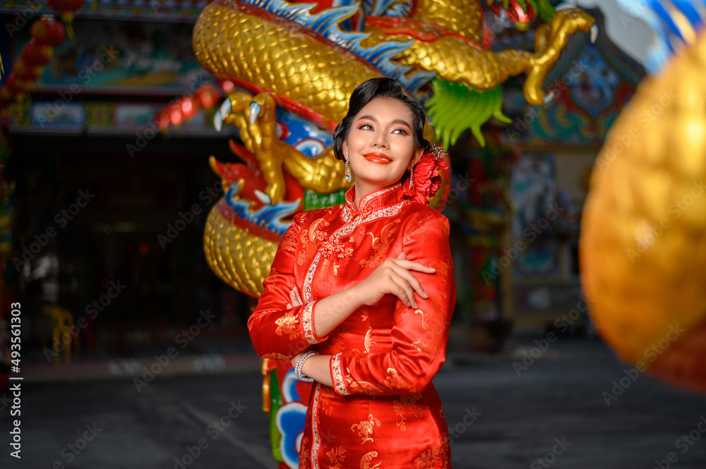 Asian beautiful woman wearing a cheongsam poses at shrine on Chinese New Year