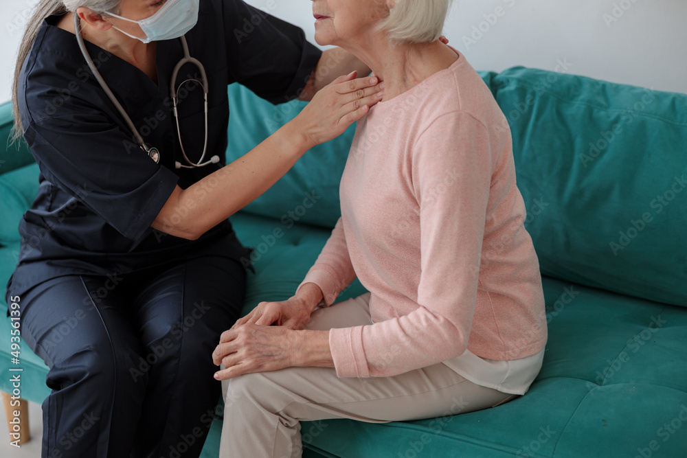 Medical worker touching a neck of an elderly woman Medical worker touching a neck of an elderly woman