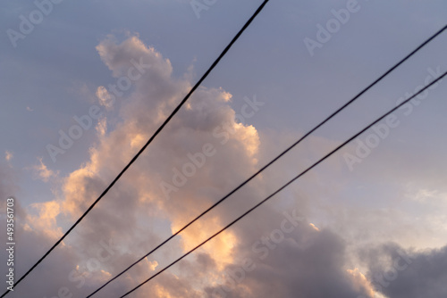 fluffy pink clouds at sunset against black telegraph wires 