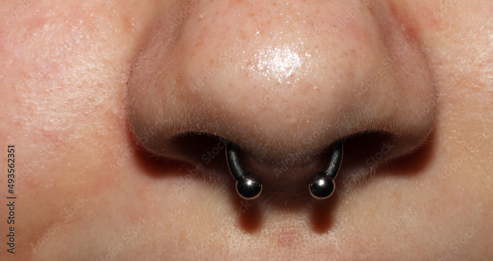 Girl's nose piercing. Septum piercing. Macro. Titanium piercing jewelry  with balls. Photos | Adobe Stock