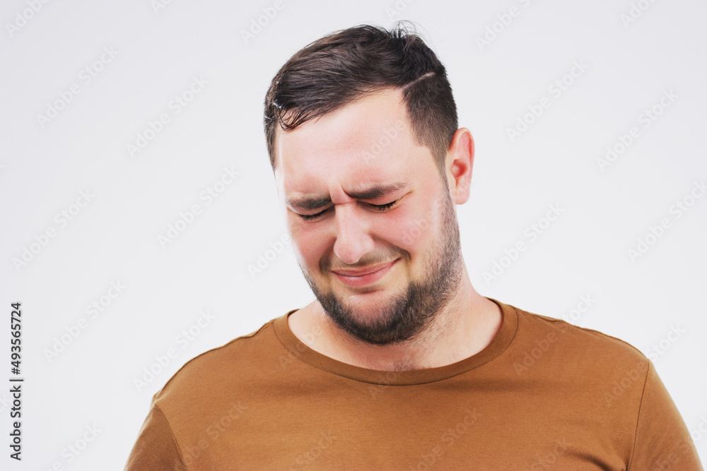 Fototapeta premium She broke my heart. Studio shot of a young man crying while standing against a gray background.