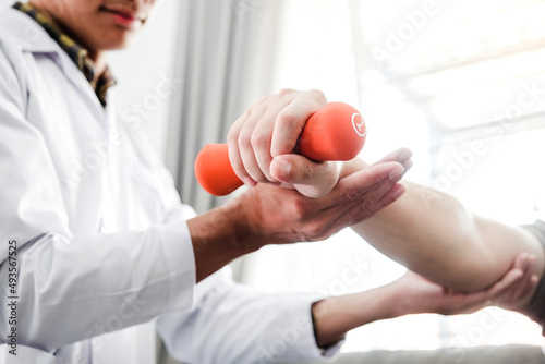 Physiotherapist man giving exercise with dumbbell treatment About Arm and Shoulder of athlete male patient Physical therapy concept