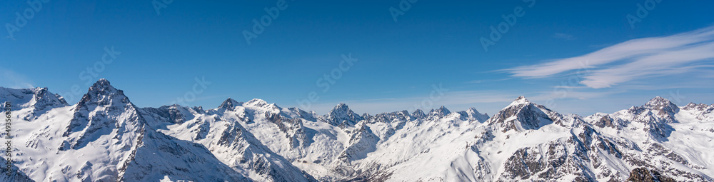 Panoramic view of winter snowy mountains in Caucasus region in Russia with blue sky