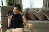 Smiling young woman using smart phone video call with her friends.