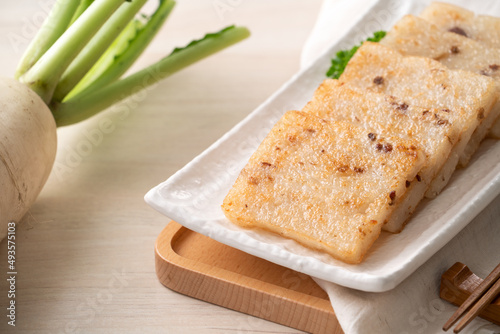 Delicious Chinese radish cake in a plate on wooden table background. photo