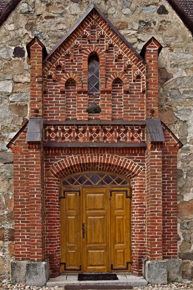 A heavily carved ornate wooden church door. Brick decorations surrounding the door.