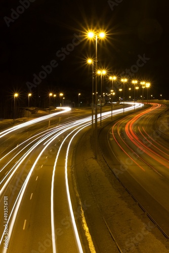 Night on the highway the front and rear lights of the cars shine. Highway with a curve and lamps shining.