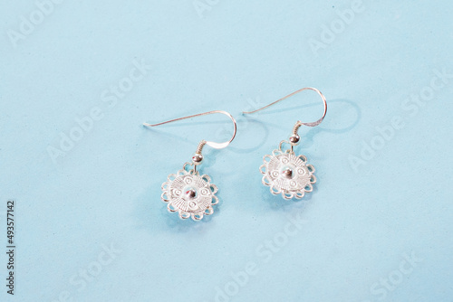 A pair of silver earrings on blue background photo