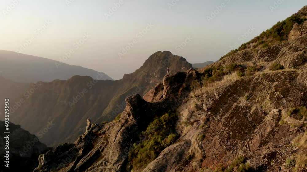 Drone orbit around man hiker standing on edge of a cliff at Madeira island, Portugal. Aerial view of mountains near Pico Grande summit Drone orbit around man hiker standing on edge of a cliff at Madeira island, Portugal. Aerial view of mountains near Pico Grande summit