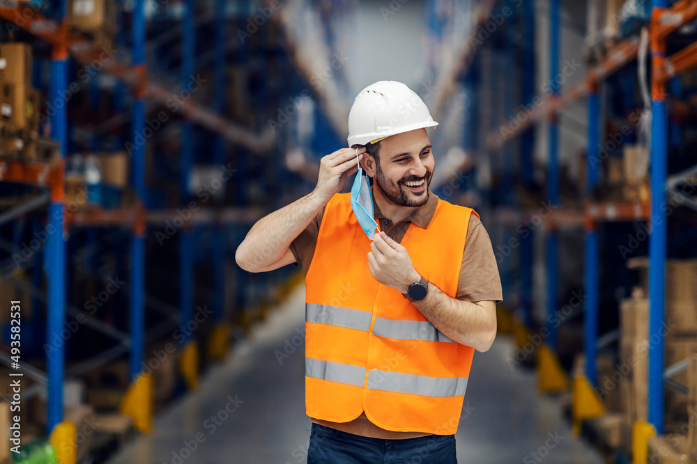A happy warehouse worker putting on mask during corona virus. A happy warehouse worker putting on mask during corona virus.