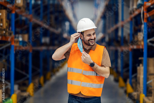 A happy warehouse worker putting on mask during corona virus.