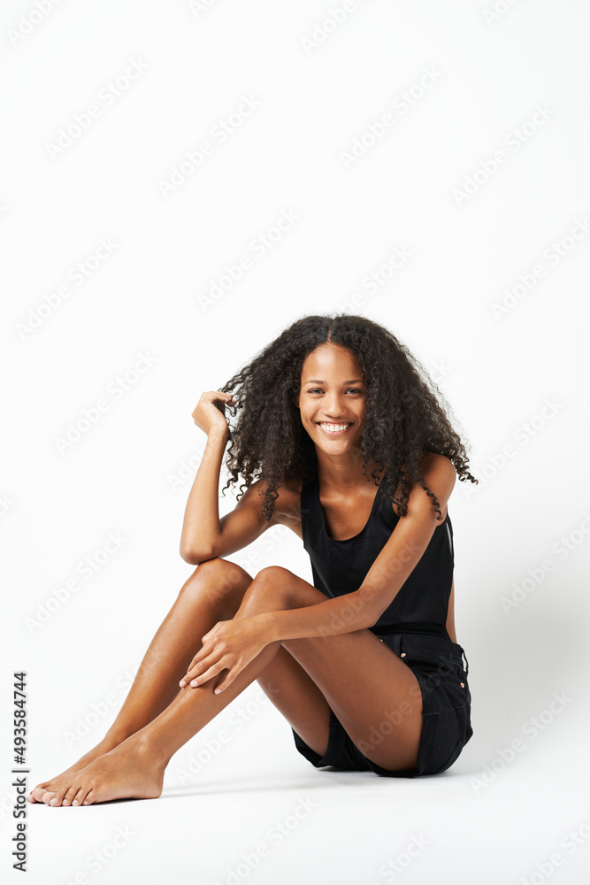 Shes perfect and playful. A full length studio shot of a beautiful young woman sitting.