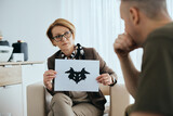 Mature psychiatrist evaluates mental disorder of soldier with inkblot test during counseling at her office.