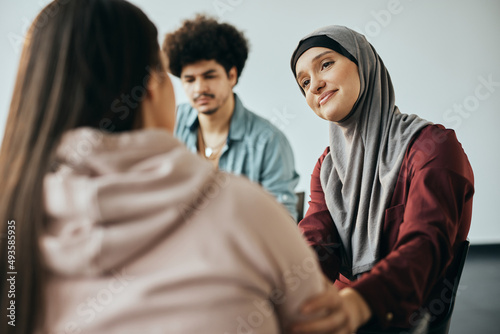Muslim woman supporting new attender of group therapy to talk about herself during meeting at mental health center.