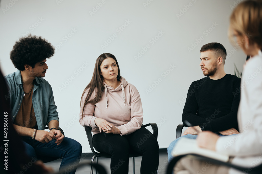 Obraz premium Young woman talks about herself during group therapy at mental health center.