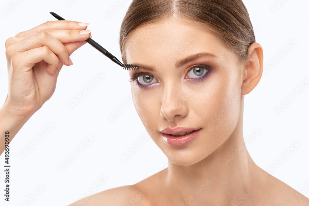Makeup artist combs eyebrows in a beauty salon. Professional make-up and cosmetic skin care.