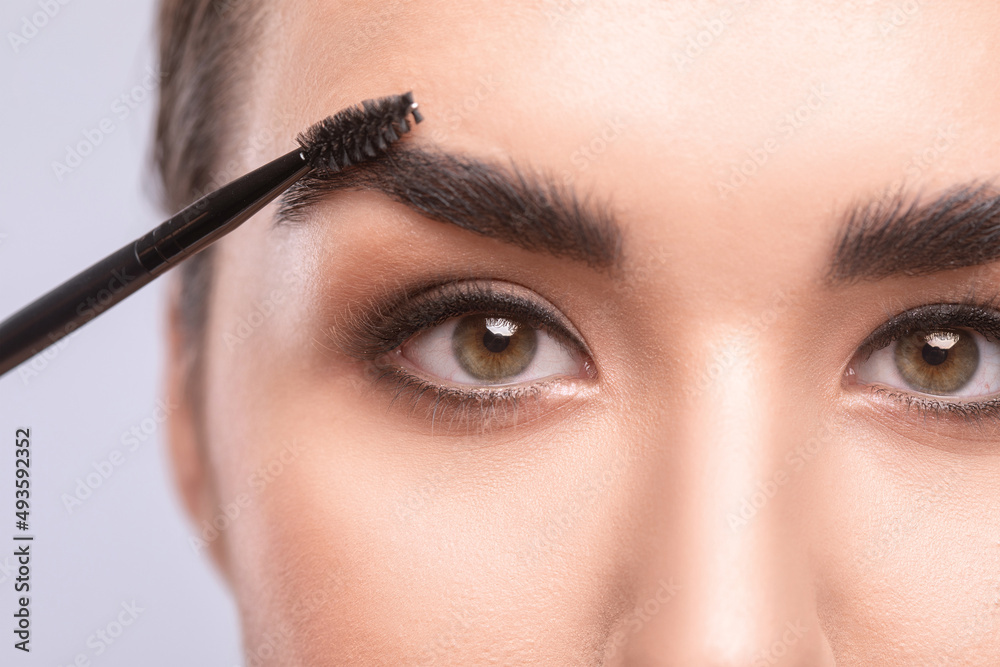 Makeup artist combs and plucks  eyebrows in a beauty salon. Professional make-up and cosmetic skin care.