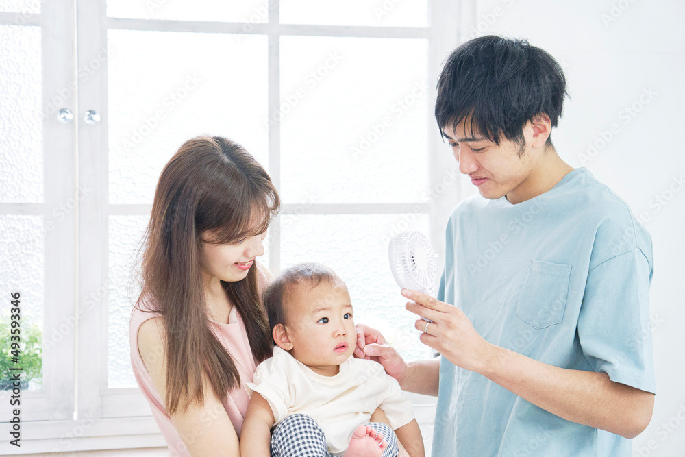 赤ちゃんにハンディファンを使う父親 赤ちゃんにハンディファンを使う父親