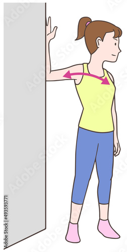 壁を使って大胸筋のストレッチをする女性