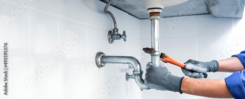 Fotografia Technician plumber using a wrench to repair a water pipe under the sink
