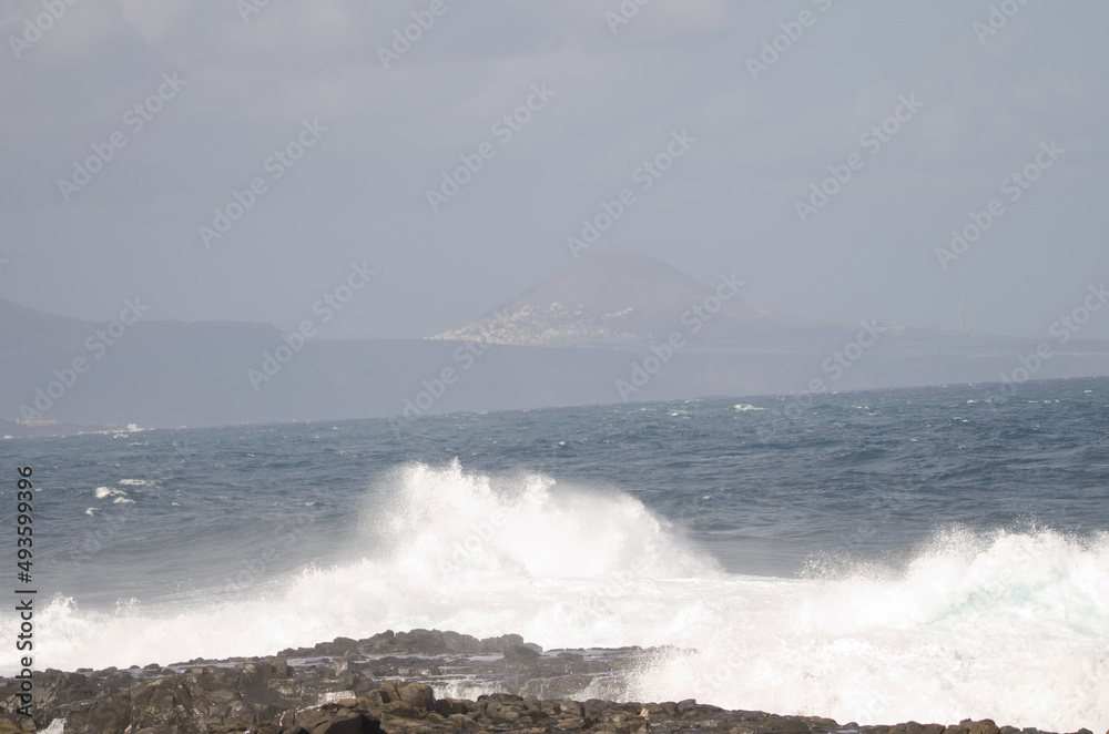 Wave breaking against the shore and Galdar Mountain. El Confital. La Isleta. Las Palmas de Gran Canaria. Gran Canaria. Canary Islands. Spain.