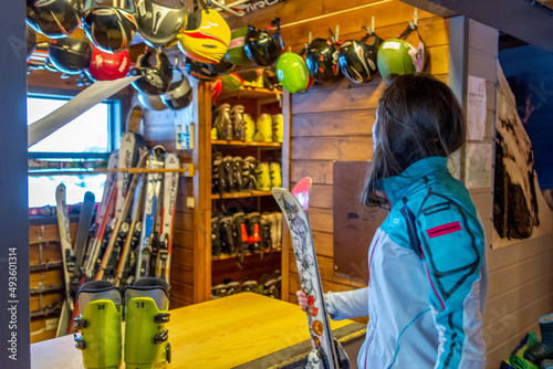 Φωτογραφία Woman Renting Ski Equipment at Ski Resort Shop Helmets in Background