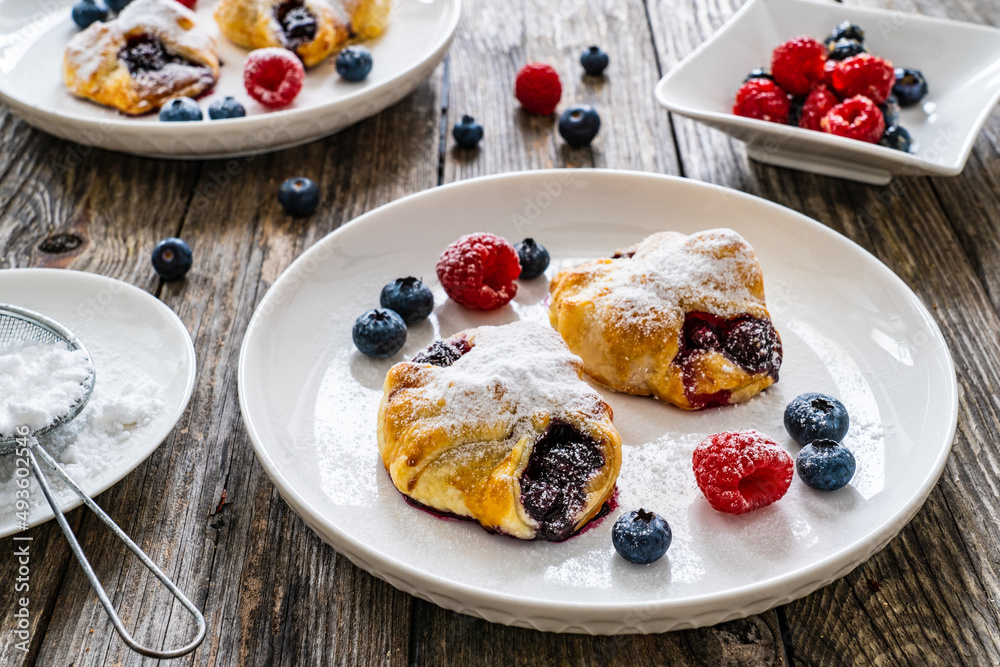 Puff pastry with raspberries and blueberries on wooden table

