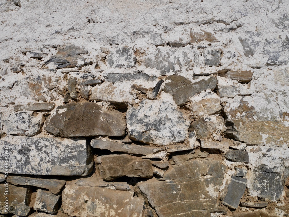 Fototapeta premium Close up of old barn facade. Stone wall with crumbling white plaster.