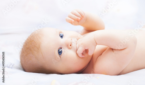 cute blue-eyed baby in her cozy white bed
