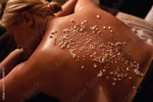 Woman back with salt during having scrub in spa